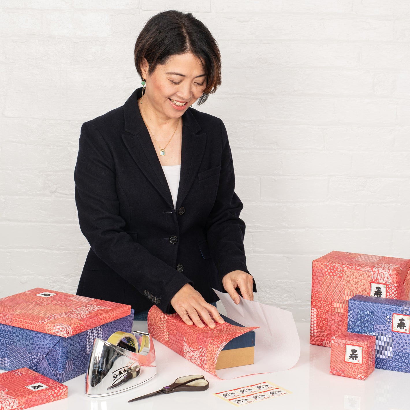 Smiling woman in a smart blazer wraps git in traditional Japanese style