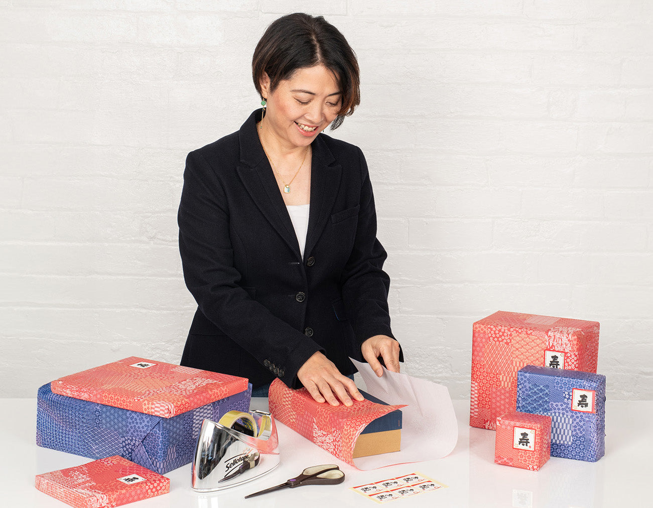 Smiling woman in a smart blazer wraps git in traditional Japanese style