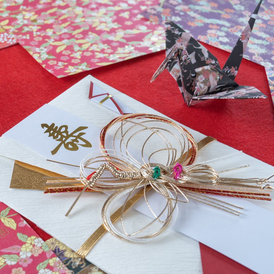 A stylish Japanese shugi-bukuro with a mizuhiki knot , complemented by colourful origami and crane