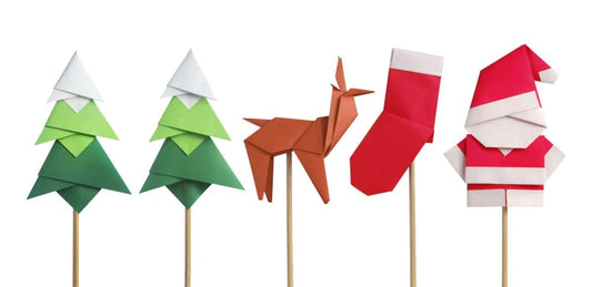 Five Christmas origami figurines on sticks including two Christmas trees, a reindeer, a stocking and Santa.