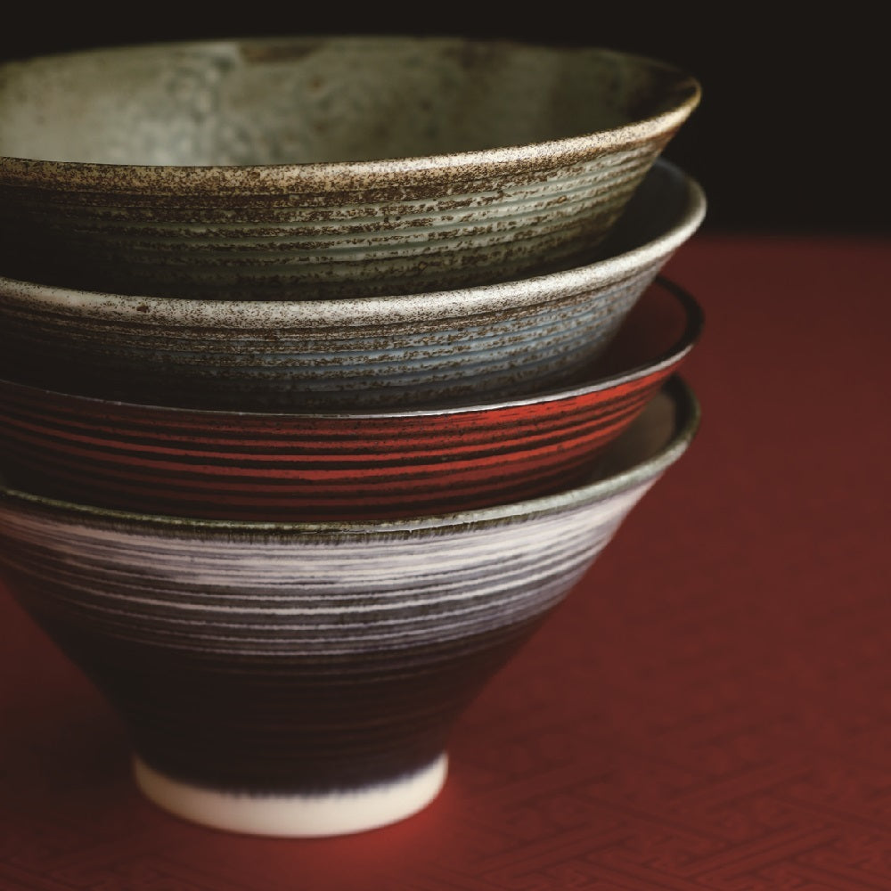 Stack of varied ceramic bowls on a deep red backdrop