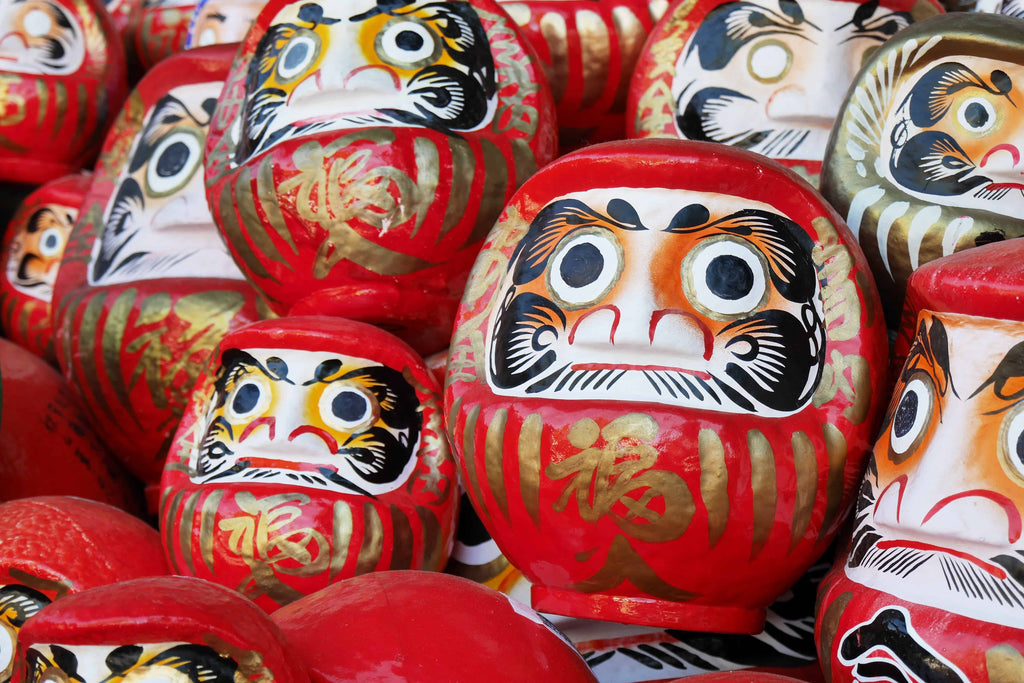 A zoomed-in view of multiple vibrant red Japanese daruma dolls