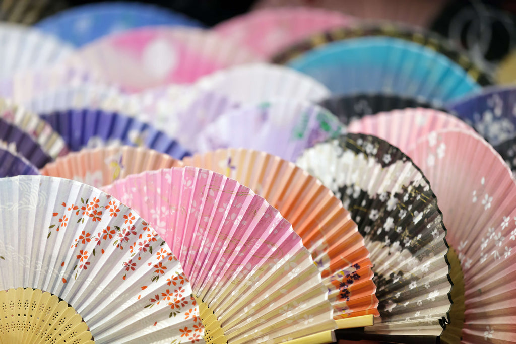 A vivid showcase of traditional hand fans, displaying varied colours and floral patterns