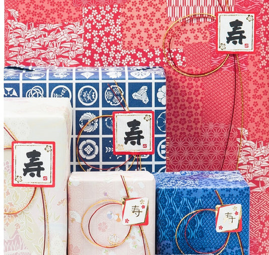 Japanese gift wrapping featuring colourful traditional washi paper and decorative mizuhiki cords, with tags bearing kanji characters.